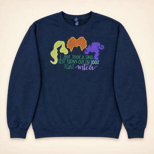 Navy 100% That Witch embroidered and glitter sweatshirt, neatly arranged on a warm ivory studio background