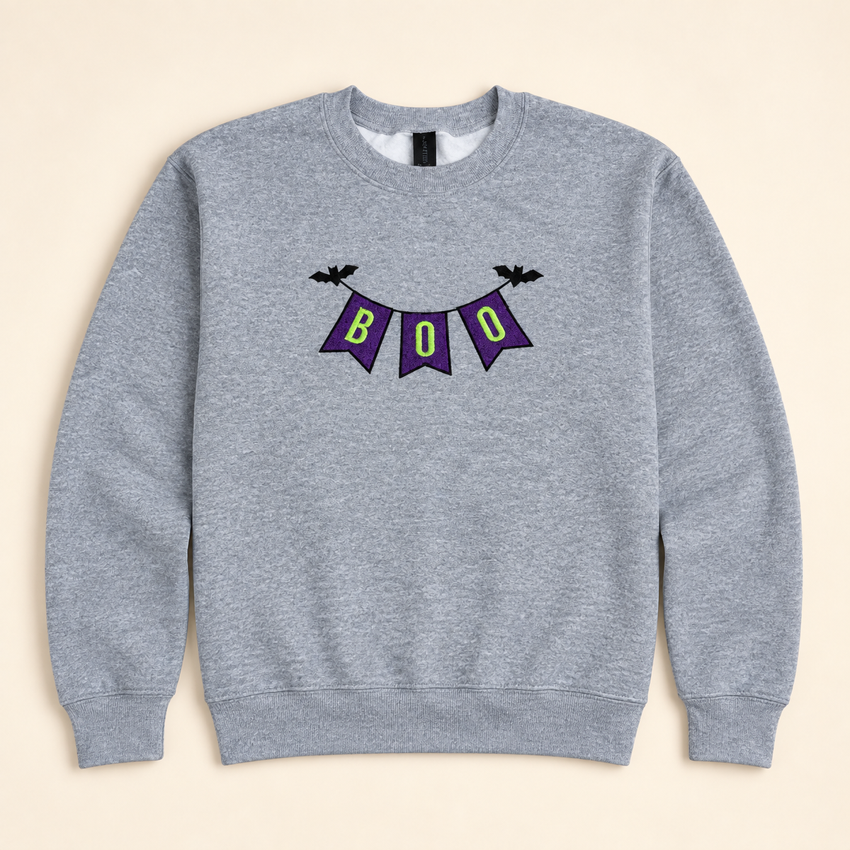 Heather gray BOO Banner embroidered sweatshirt, neatly arranged on a warm ivory studio background
