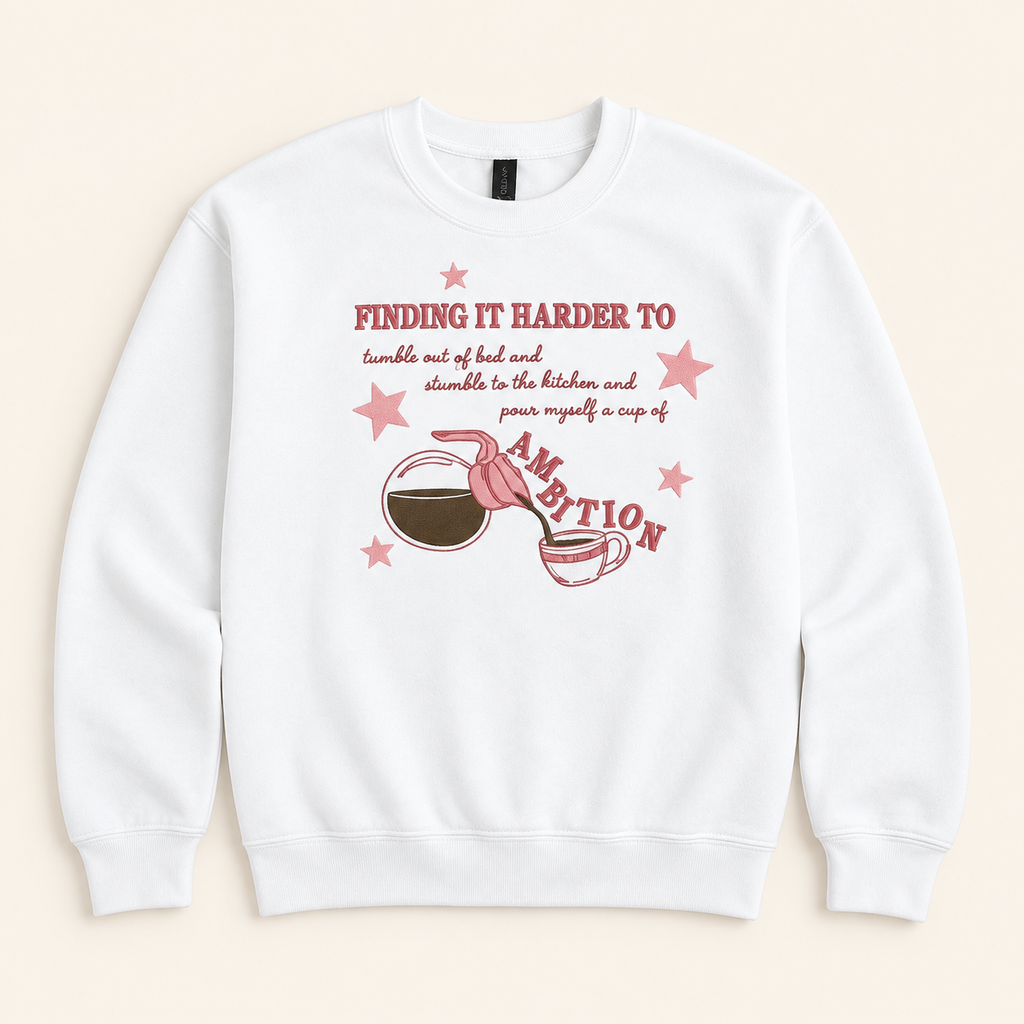 White Cup of Ambition embroidered sweatshirt, neatly arranged on a warm ivory studio background