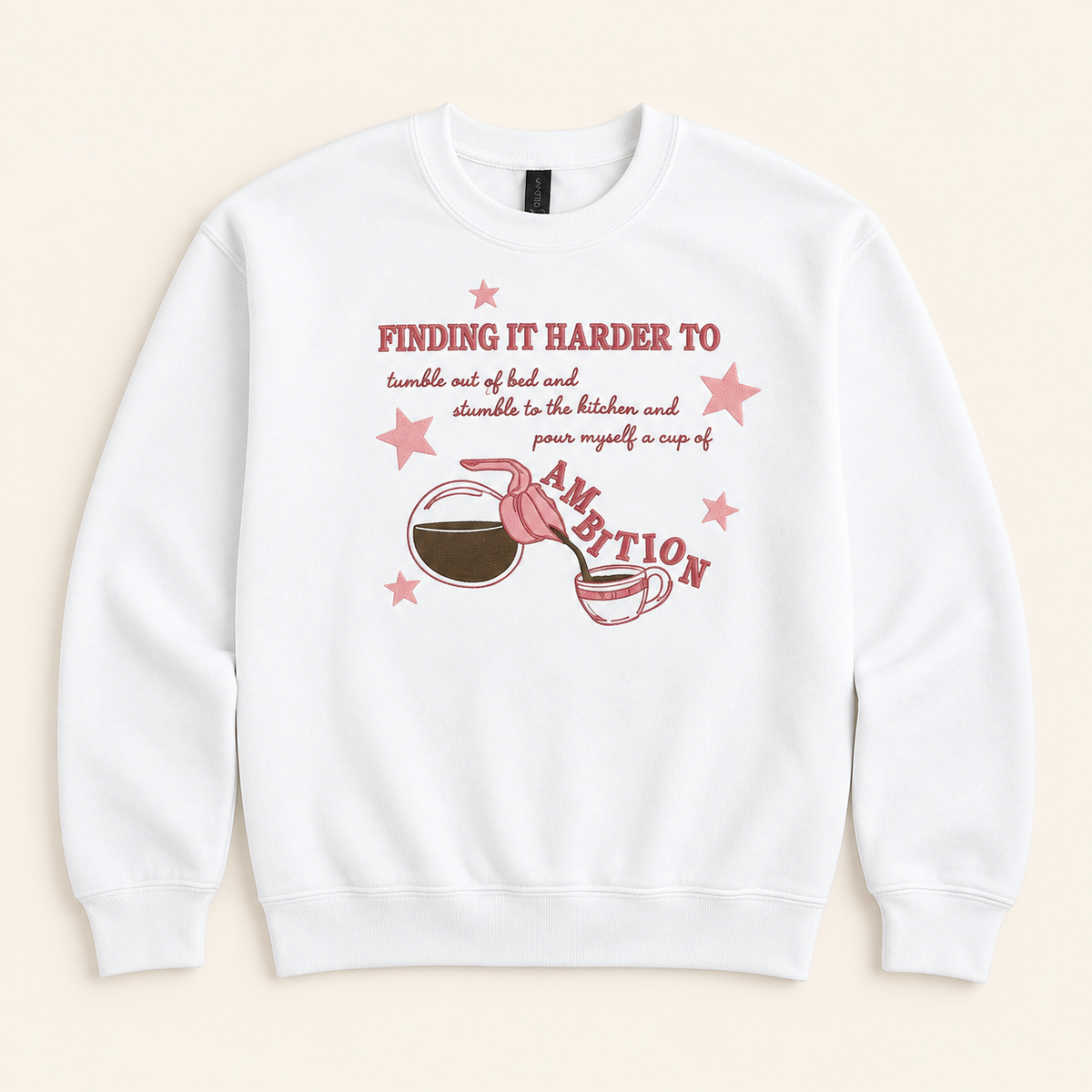 White Cup of Ambition embroidered sweatshirt, neatly arranged on a warm ivory studio background