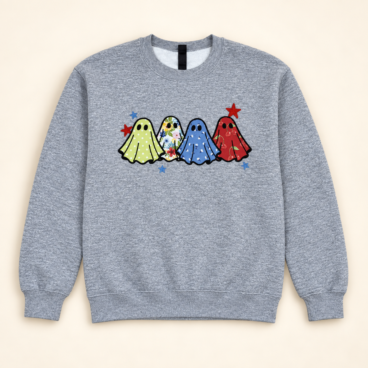 Heather gray sweatshirt with four patterned ghost appliqués, neatly arranged on a warm ivory studio background