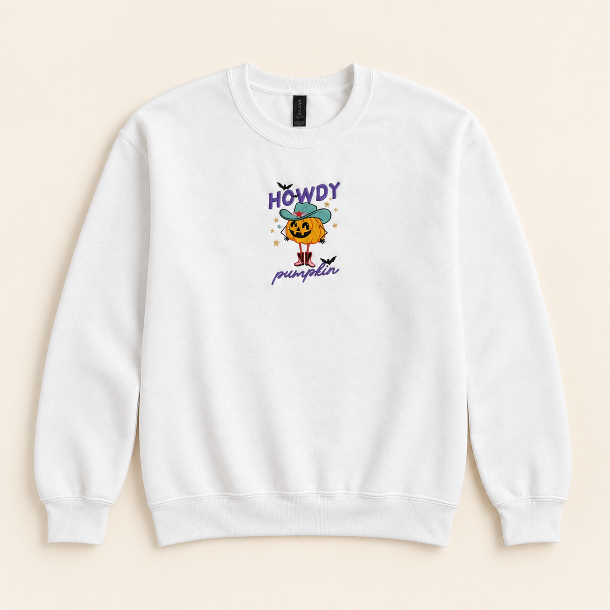 White Howdy Pumpkin embroidered sweatshirt, neatly arranged on a warm ivory studio background