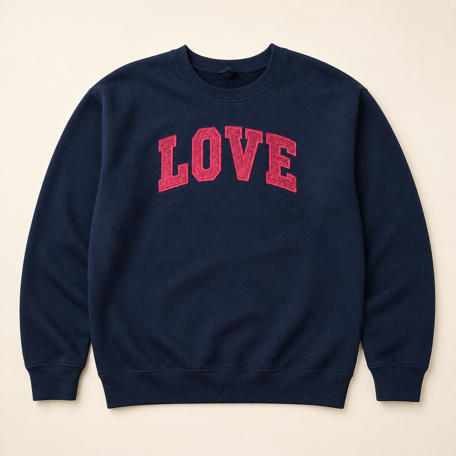 Navy LOVE embroidered and glitter sweatshirt on a warm ivory studio background