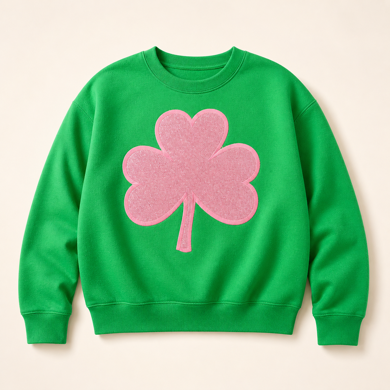 Green sweatshirt with a pink glitter shamrock appliqué on a warm ivory studio background